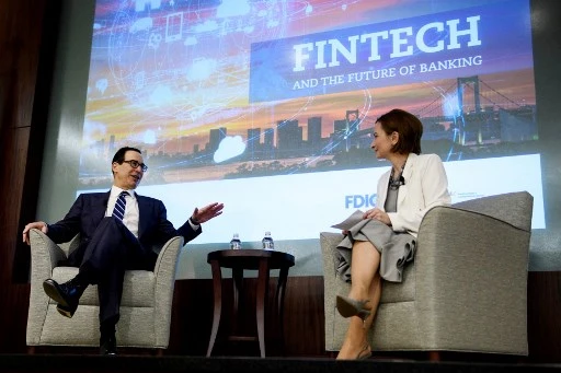 La présidente de la Federal Deposit Insurance Corporation (FDIC), Jelena McWilliams (à droite), écoute pendant que le secrétaire américain au Trésor Steven Mnuchin s'exprime lors d'une conférence sur « Les technologies financières et l'avenir de la banque », à la FDIC le 24 avril 2019, à Arlington, Virginie. (Brendan Smialowski/AFP)