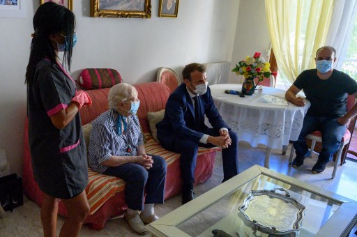 Le président français Emmanuel Macron rend visite à Gisèle Charles, 80 ans, qui vit seule à Toulon, dans le sud de la France, le 4 août 2020, dans le cadre de rencontres avec des aides à domicile. (Christophe Simon/Pool/AFP)