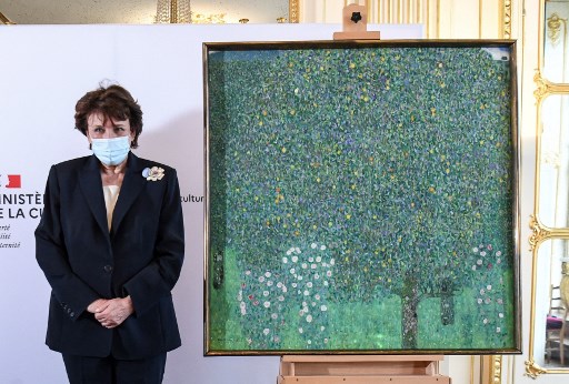 La ministre française de la Culture Roselyne Bachelot pose à côté du tableau «Rosiers sous les arbres» (1905) du peintre autrichien Gustav Klimt, au Musée d'Orsay à Paris, le 15 mars 2021. Le tableau sera restitué à la famille de Nora Stiasny, victime de la Shoah, dépossédée de l’œuvre lors d'une vente forcée en août 1938. (Alain Jocard /AFP/Pool)