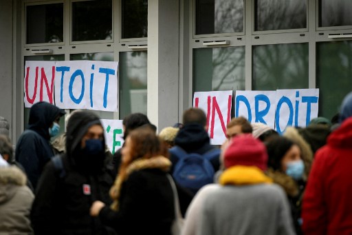 Des enseignants et des bénévoles du DAL (Droit au logement) se rassemblent près d'une pancarte indiquant «Un toit, c'est un droit» devant l'école primaire Sylvain Dauriac pour alerter sur les conditions de vie de certaines familles dont les enfants fréquentent cette école, à Toulouse, dans le sud-ouest de la France, en décembre 8 décembre 2021. (Valentin Chapuis/AFP)