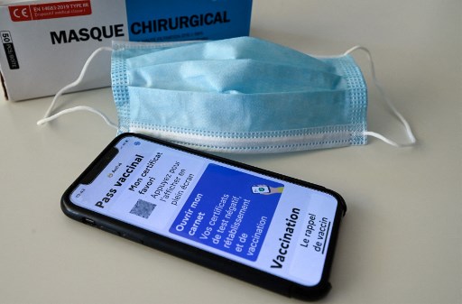 Photographie d'illustration prise le 27 janvier 2022, à Montpellier, montrant un masque facial et un pass sanitaire (pass vaccinal) sur un écran de téléphone portable connecté à l'application de traçage Covid-19 '#TousAntiCovid'. (Pascal Guyot / AFP)