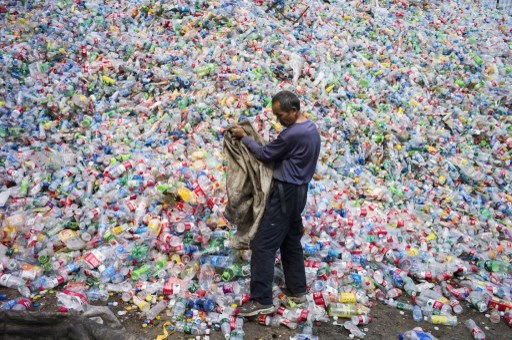 Cette photo prise le 17 septembre 2015 montre un ouvrier chinois en train de trier des bouteilles en plastique pour les recycler dans le village de Dong Xiao Kou, à la périphérie de Pékin. (Fréd Dufour/AFP)