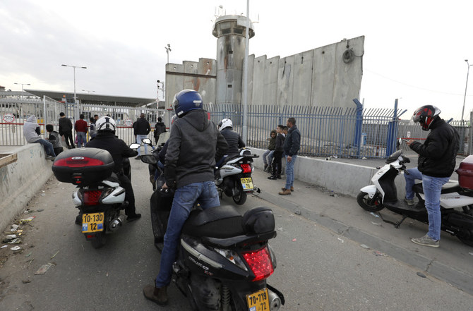 Des cyclistes palestiniens attendent au poste de contrôle temporairement fermé de Qalandia au passage entre la ville cisjordanienne de Ramallah et Jérusalem-Est occupée par Israël, le 7 décembre 2020. (AFP)