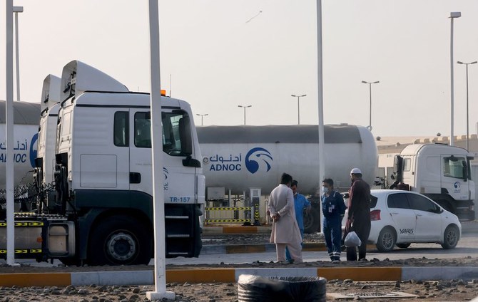 Des hommes se tiennent devant une installation de stockage de l'ADNOC à Abou Dhabi, le 17 janvier 2022. Trois personnes ont été tuées lundi lors d'une attaque présumée par drone contre les installations de l'ADNOC. (AFP)
