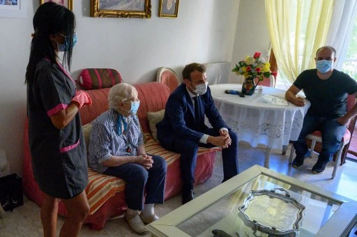 Le président français Emmanuel Macron rend visite à Gisèle Charles, 80 ans, qui vit seule à Toulon, dans le sud de la France, le 4 août 2020, dans le cadre de rencontres avec des aides à domicile. (Christophe Simon/Pool/AFP)
