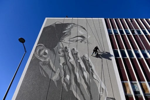 L'artiste de rue français Mahn Kloix peint une fresque représentant Tursunay Ziawudum, une ancienne détenue ouïghoure qui a quitté la Chine et a parlé publiquement de son expérience d'internement, à Marseille, dans le sud de la France, le 7 octobre 2021. (Nicolas Tucat/AFP)