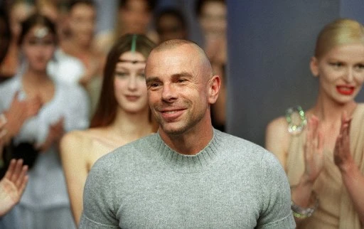 Dans cette photo d'archive prise le 3 octobre 1999, le couturier français Thierry Mugler est acclamé par ses mannequins et le public après la présentation de sa collection de prêt-à-porter printemps-été 2000 à Paris. (Thomas Coex/AFP)