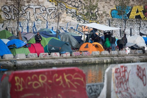 Un homme se tient parmi des tentes dans un camp de migrants de fortune, principalement composé d'Afghans, le long du canal Saint-Martin à Paris le 21 février 2018. (Joël Saget / AFP)