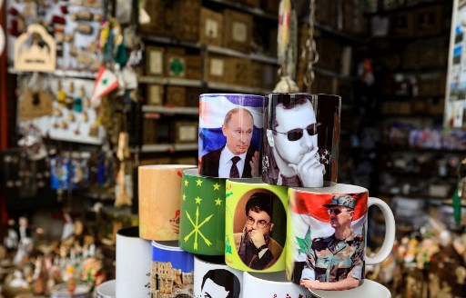 Des objets avec des images du président syrien Bachar al-Assad, du président russe Vladimir Poutine et du chef du mouvement chiite libanais Hezbollah Hassan Nasrallah, sont exposés dans une boutique de souvenirs dans le vieux quartier de la capitale syrienne Damas, le 27 février 2022. (Louai Beshara/AFP)