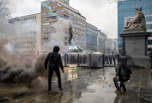 Un manifestant se tient devant les forces de l'ordre lors d'une manifestation pour "la liberté, la démocratie et les droits de l'homme" organisée par l'alliance Européens Unis à Bruxelles, le 23 janvier 2022, pour protester contre les mesures imposées par les pouvoirs publics en Belgique et dans d'autres pays européens pour lutter contre la pandémie de covid. (Hatim Kaghat/Belga/AFP)
