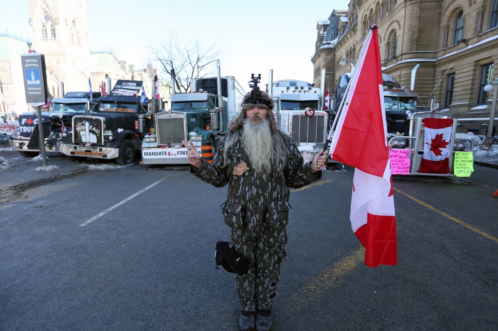 Un homme tient un drapeau canadien près du Parlement alors que les manifestants continuent de protester le 7 février 2022 à Ottawa, au Canada. (AFP)
