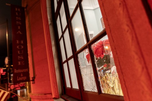 Des fleurs à travers une fenêtre brisée au restaurant et salon Russia House à Washington, DC, le 8 mars 2022. (Stefani Reynolds/AFP)