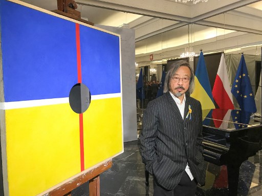 Cette photo prise le 11 mars 2022 montre l'artiste chinois Huang Rui posant avec son œuvre "Absence of Black Moon" lors d'un événement "Ensemble pour la paix" à l'ambassade de Pologne à Pékin. Patrick BAERT / AFP