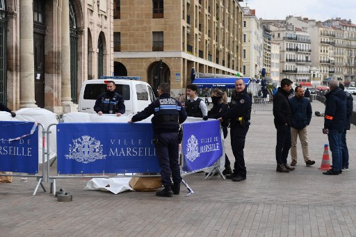 Des policiers français se tiennent à côté du corps d'un homme non identifié (à gauche) qui a tenté de poignarder des policiers municipaux français, devant l'hôtel de ville de Marseille, le 12 mars 2022. (Clément Mahoudeau/AFP