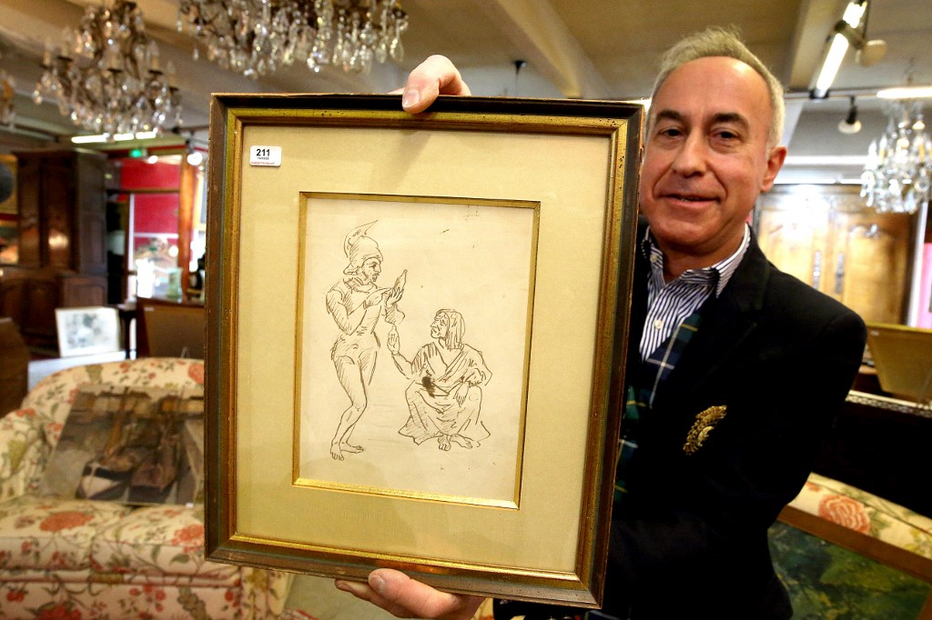 Le commissaire-priseur Thierry Collet tient un dessin de l'artiste français Paul Cézanne intitulé "Soldat et vieille femme", vers 1856-1857, lors de la vente aux enchères de la maison de vente Ivoire, la veille de sa vente, à Reims, le 13 mars 2022. (AFP).