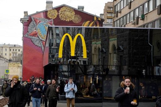 Passants, devant le restaurant phare de McDonald's sur la place Pushkinskaya - le premier de la chaîne ouvert en URSS le 31 janvier 1990 - dans le centre de Moscou le 13 mars 2022, dernier jour de McDonald's en Russie. (AFP)