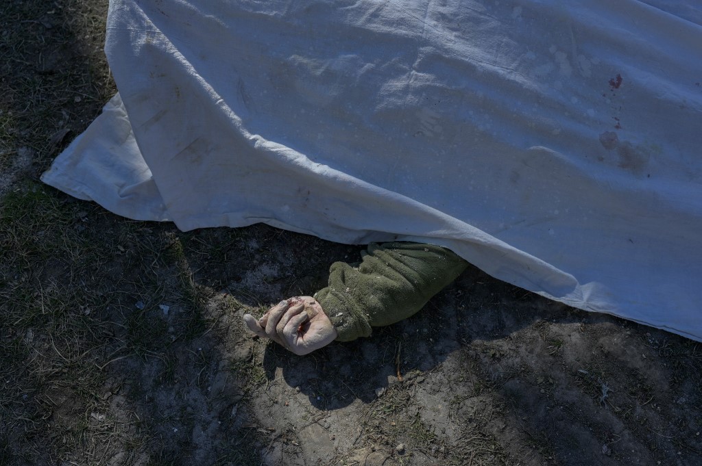 Une photo prise le 19 mars 2022 montre le corps d'un soldat ukrainien recouvert d'un drap à côté de l'école militaire touchée par des roquettes russes la veille, à Mykolaiv, dans le sud de l'Ukraine. (AFP).