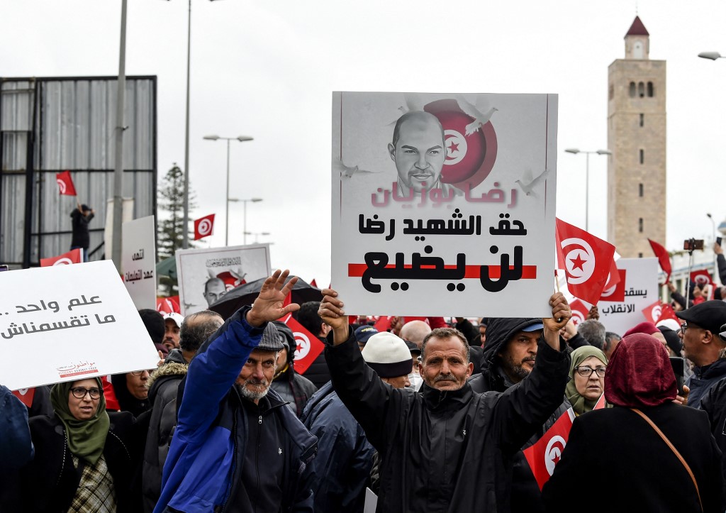 Des manifestants tunisiens brandissent des pancartes et des drapeaux nationaux lors d'une manifestation contre leur président, près du siège de l'Assemblée tunisienne (parlement), dans la capitale Tunis, le 20 mars 2022. (AFP).