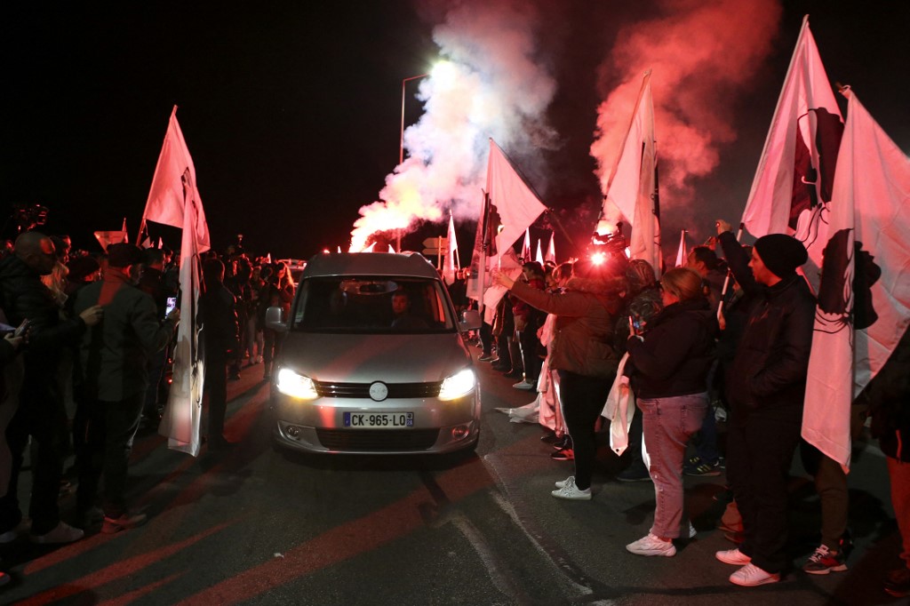 Des personnes tiennent des drapeaux corses et des bougies alors que le corbillard transporte le corps du militant indépendantiste corse Yvan Colonna à son arrivée sur l'île méditerranéenne française de Corse, le 23 mars 2022 à Ajaccio. (AFP).