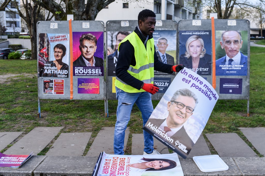 Un employé d'une société d'affichage colle l'affiche de campagne officielle du candidat présidentiel du parti "La France Insoumise" (LFI) Jean-Luc Melenchon pour l'élection présidentielle française, à Saint-Herblain, près de Nantes, dans l'ouest de la France, le 28 mars 2022 (AFP)