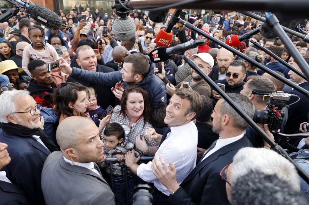 Le président français sortant et candidat du parti de droite La République en Marche (LREM) à l'élection présidentielle, Emmanuel Macron (C-D), salue des personnes alors qu'il rencontre des représentants d'associations travaillant dans le quartier de la "Fontaine d'Ouche" à Dijon, le 28 mars 2022. (AFP).