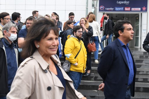 Les journalistes français Patrick Cohen (à droite) et Anne Sinclair (à gauche) participent à une manifestation, organisée par l'intersyndicale et la société des rédacteurs en chef (SDR) de la radio française Europe 1, pour dénoncer "l'influence grandissante" du groupe de médias Vivendi Vincent Bolloré et pour faire part de leur inquiétude face au rapprochement de la station de CNews le 30 juin 2021 devant l'immeuble abritant Europe 1 à Paris. (Alain Jocard / AFP)