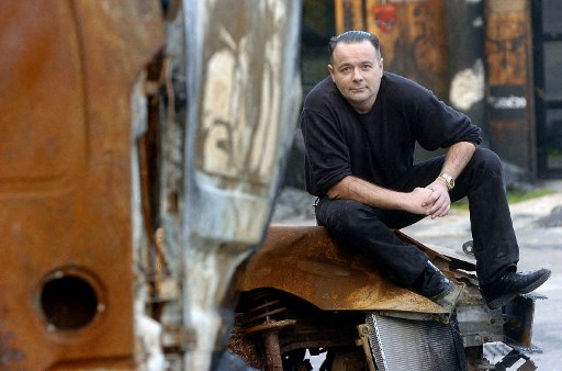 Thierry Ehrmann, fondateur du groupe Serveur et également à la tête d'Artprice, leader mondial des banques de données sur la cotation et les indices de l'art, pose, le 24 novembre 2004 à Saint-Romain-au-Mont-d'Ou, devant le siège social de son groupe appelé «La Demeure du Chaos». (Martin Bureau/AFP)