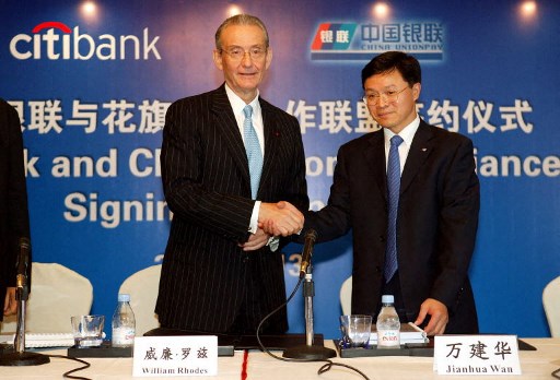 William Rhodes (à gauche), président du géant bancaire américain Citibank, serre la main de Wan Jianhua (à droite), président d'UnionPay, qui exploite le réseau national de cartes bancaires de la Chine, après avoir signé un accord lors de l'ouverture de la succursale phare de Citibank à Shanghai le 13 septembre 2005. (RST/AFP)