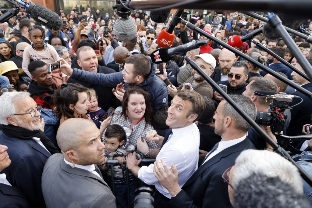 Le président français sortant et candidat du parti de droite La République en Marche (LREM) à l'élection présidentielle, Emmanuel Macron (C-D), salue des personnes alors qu'il rencontre des représentants d'associations travaillant dans le quartier de la "Fontaine d'Ouche" à Dijon, le 28 mars 2022. (AFP).