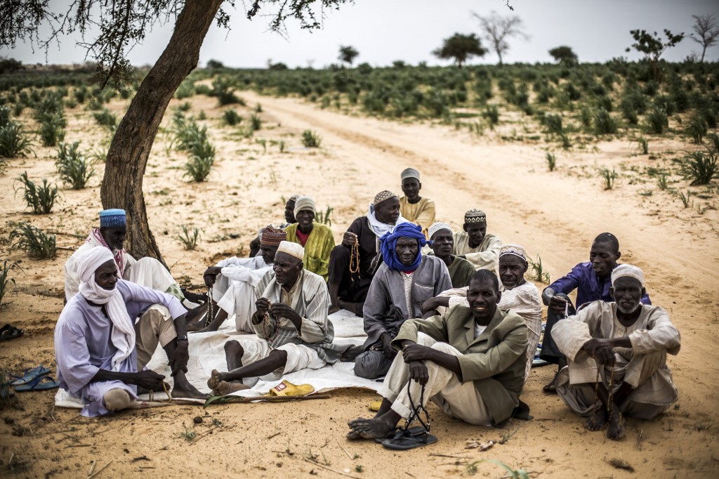 Un groupe d'homme se rassemble pour prier sous un arbre dans un village près de Tanout, dans la région de Zinder, au Niger, le 3 août 2019. (AFP).