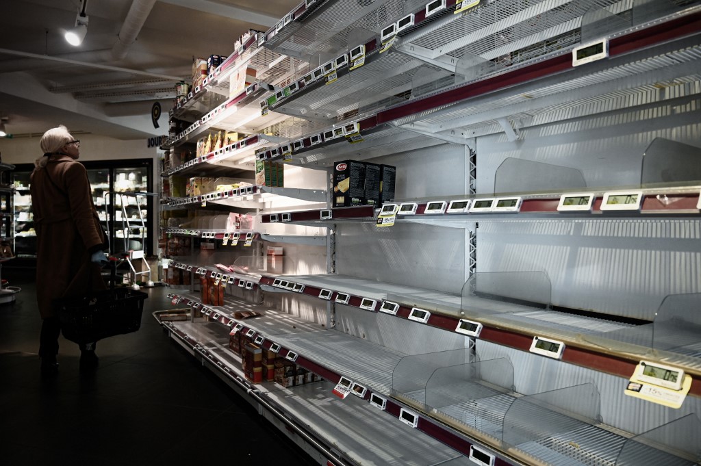 Une femme se tient à côté d'une étagère vide dans un supermarché à Paris, le 15 mars 2020. Les gens faisaient des provisions de produits alimentaires en raison de l'épidémie de COVID-19. (AFP).