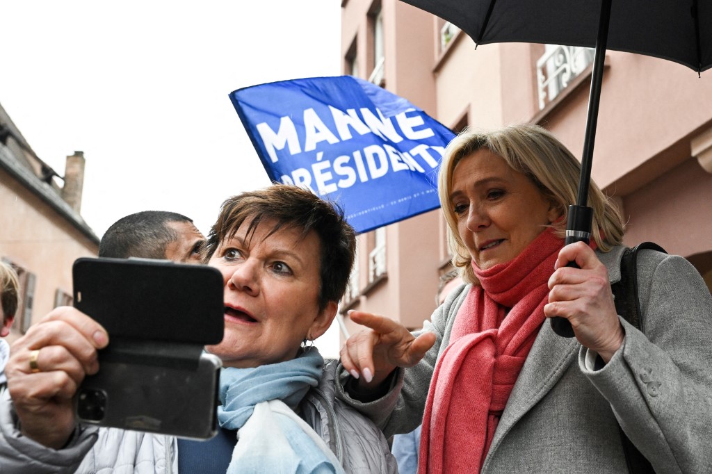 Marine Le Pen, députée du parti d'extrême droite Rassemblement national et candidate à l'élection présidentielle française, fait un geste à côté d'une partisane après une visite du marché de Haguenau, dans l'est de la France, le 1er avril 2022. (AFP)