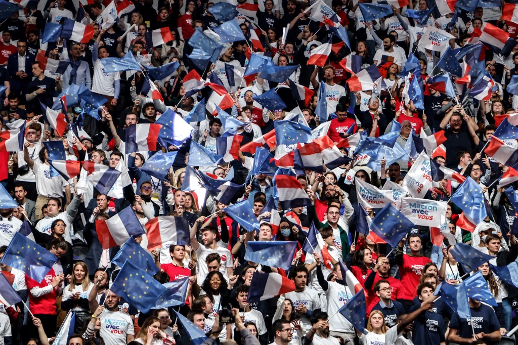 Des partisans du président français et candidat à la réélection du parti libéral La République en Marche (LREM) Emmanuel Macron agitent des drapeaux français et européens avant le début du premier meeting de campagne de Macron à l'arène de Paris La Défense à Nanterre, dans la banlieue de Paris, le 2 avril 2022. (AFP).