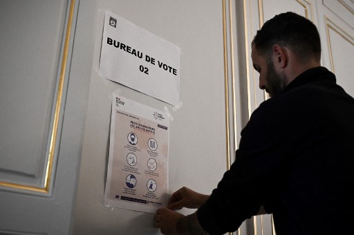 Un employé municipal accroche des affiches d'information liées au Covid-19 lors des préparatifs du premier tour de l'élection présidentielle française à l'hôtel de ville de Bordeaux le 9 avril 2022. (Philippe Lopez/AFP)
