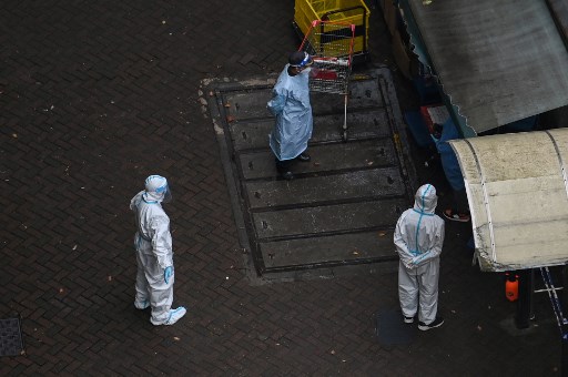 Des travailleurs portant un équipement de protection individuelle (EPI) se tiennent à l'entrée d'un complexe lors d'un verrouillage du coronavirus Covid-19 dans le district de Jing'an à Shanghai le 14 avril 2022. (Hector Retamal/AFP)