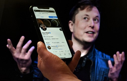Dans cette photo d'illustration, un écran de téléphone affiche le compte Twitter d'Elon Musk avec une photo de lui en arrière-plan, le 14 avril 2022, à Washington, DC. (Olivier Douliery/AFP)