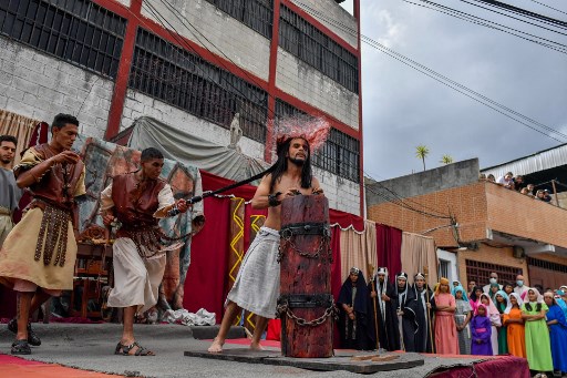Un acteur campant Jésus-Christ est flagellé par un autre acteur dépeignant des soldats romains alors qu'ils rejouent La Passion de Jésus-Christ lors de la procession du Vendredi Saint dans le bidonville de Petare à Caracas, le 15 avril 2022. (Federico Parra/AFP)