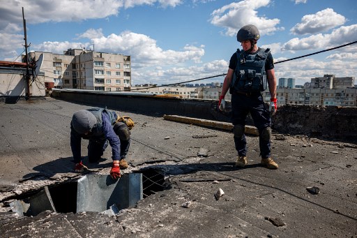 Des membres d'une équipe de déminage du Service national d'urgence d'Ukraine vérifient le toit d'un immeuble résidentiel à la recherche d'engins non explosés à la suite d'un bombardement russe à Kharkiv, dans l'est de l'Ukraine, le 28 avril 2022, le 64e jour de l'invasion russe de l'Ukraine. (Dimitar Dilkoff/AFP)