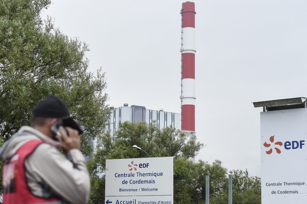 Un employé d'EDF (Electricité de France) se tient à l'entrée de la centrale électrique à charbon d'EDF de Cordemais, lors d'un rassemblement pour protester contre l'abandon du projet Ecocombust qui consiste à remplacer le charbon par des pellets de biomasse densifiée, Cordemais, ouest de la France, le 13 juillet 2021. (AFP)