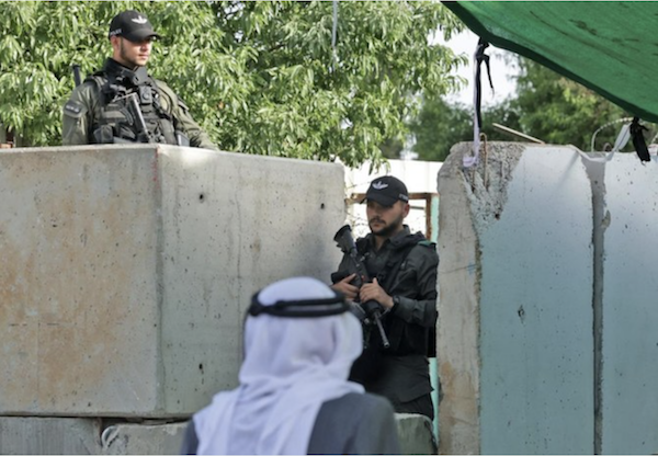 Les forces de sécurité israéliennes surveillent les Palestiniens qui traversent un poste de contrôle pour se rendre à Jérusalem pour les prières du vendredi dernier du Ramadan dans l'enceinte de la mosquée Al-Aqsa, le 29 avril 2022. (AFP)