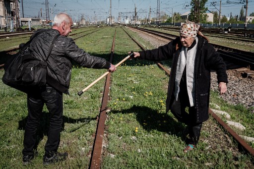 Un couple âgé traverse des voies ferrées au lieu d'utiliser un survol pour se rendre à l'arrêt de bus avant l'évacuation de Lyman, dans l'est de l'Ukraine, le 28 avril 2022, au milieu de l'invasion russe de l'Ukraine. (Yasuyoshi Chiba / AFP)