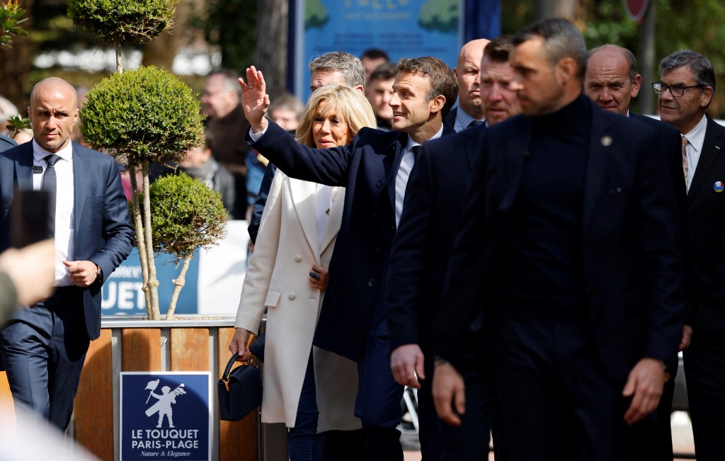 Le président français Emmanuel Macron et son épouse Brigitte Macron s'entretiennent avec les spectateurs avant de voter pour le premier tour de l'élection présidentielle française dans un bureau de vote du Touquet, dans le nord de la France, le 10 avril 2022 (Photo, AFP).