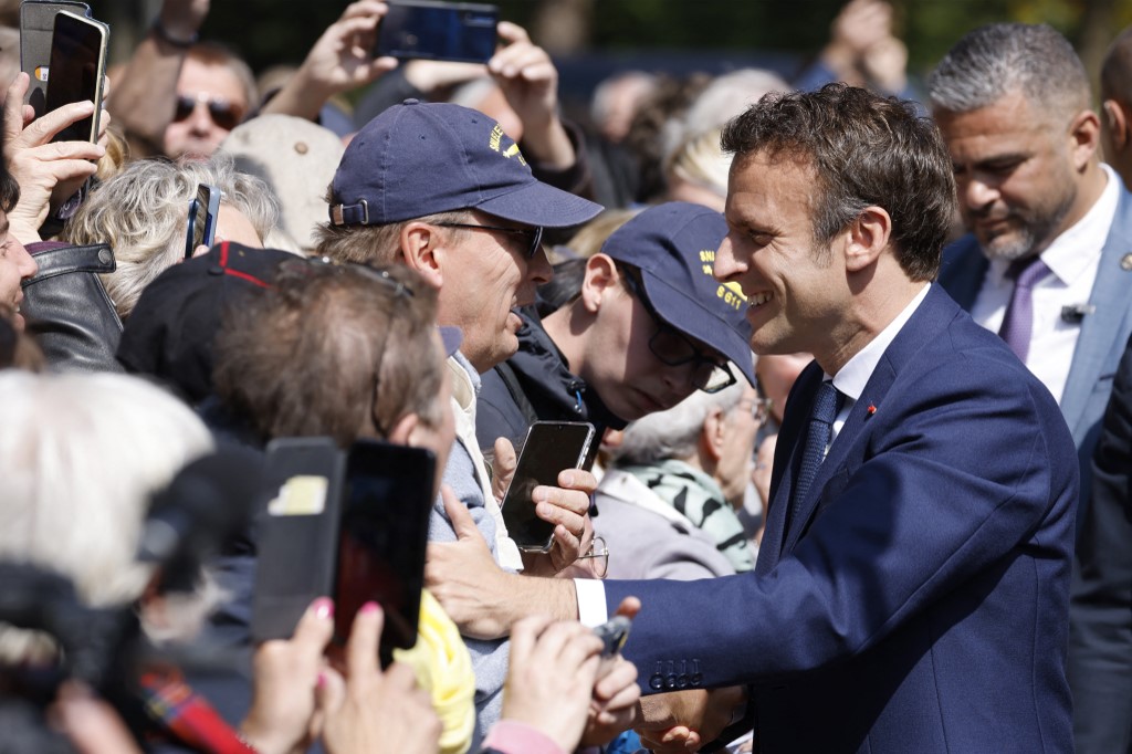Le président français Emmanuel Macron serre la main des gens alors qu'il arrive pour voter (Photo, AFP).