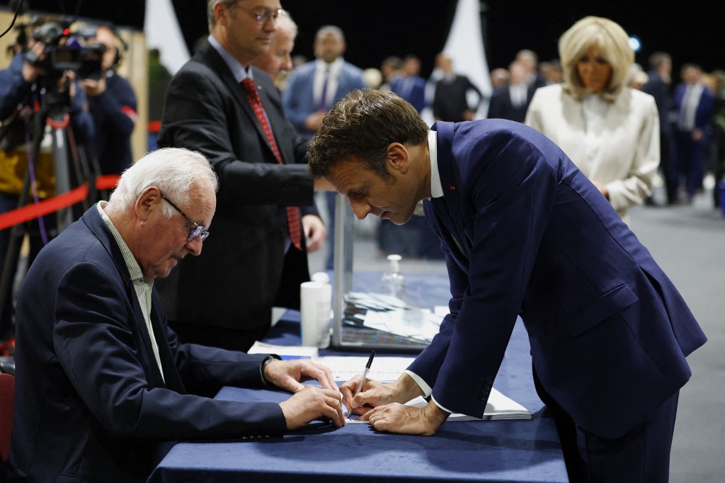 Le président français Emmanuel Macron, candidat à sa réélection, signe le registre électoral après avoir voté pour le second tour de l'élection présidentielle française dans un bureau de vote du Touquet, dans le nord de la France, le 24 avril 2022 (Photo, AFP).
