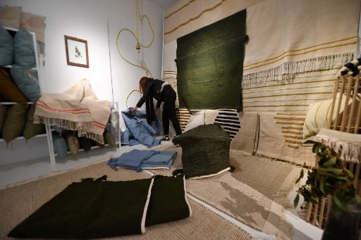 Une vendeuse arrange des tapis tissés par des femmes dans l'oasis de Nefta, dans le sud-ouest de la Tunisie, dans un magasin géré par Shanti, une entreprise sociale qui aide les artisans de tout le pays d'Afrique du Nord, dans la capitale Tunis, le 15 avril 2022. (Fethi Belaid/AFP)