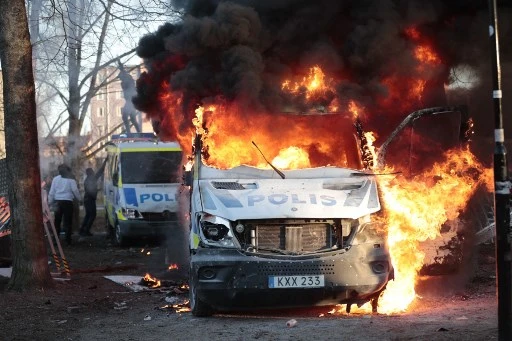 Des fourgons de police en feu lors d'une contre-manifestation dans le parc Sveaparken à Orebro, dans le centre-sud de la Suède, le 15 avril 2022, où le parti d'extrême droite danois Stram Kurs a obtenu l'autorisation de se réunir le vendredi saint. (Kicki Nilsson/Agence de presse TT/AFP)