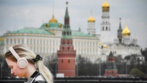 Une fille marche le long d'un pont sur la Moskova avec le Kremlin en arrière-plan le 27 avril 2022 à Moscou. (AFP)
