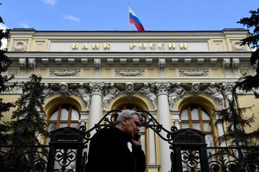 Un passant devant le siège de la Banque centrale de Russie surmontée du drapeau russe dans le centre-ville de Moscou, le 19 mars 2021. (Kirill Kudryavtsev/AFP)