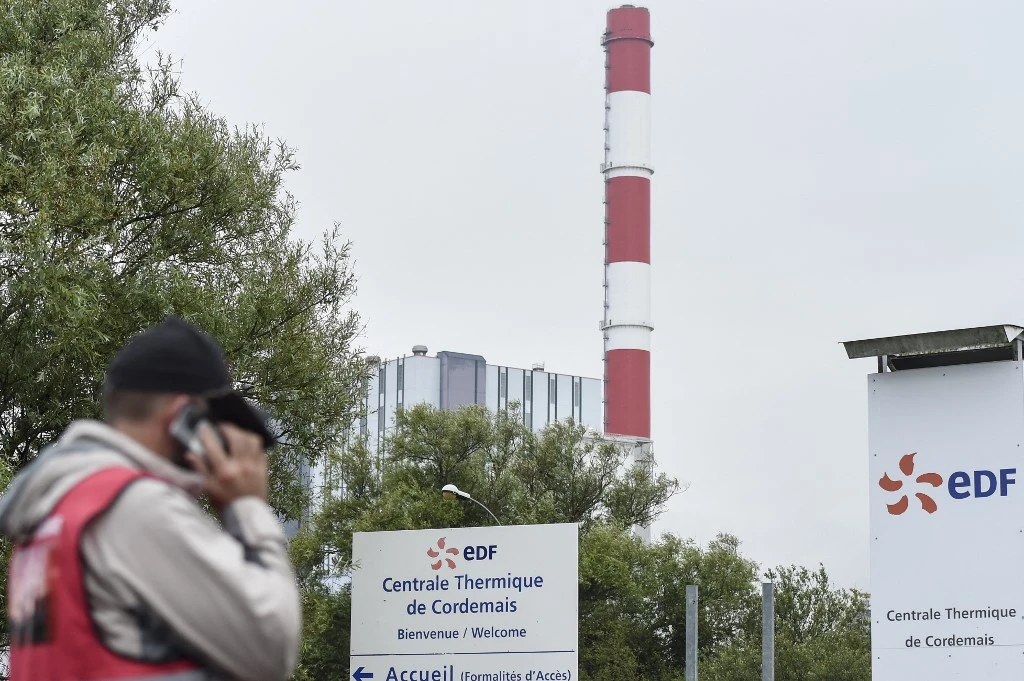 Un employé d'EDF (Electricité de France) se tient à l'entrée de la centrale électrique à charbon d'EDF de Cordemais, lors d'un rassemblement pour protester contre l'abandon du projet Ecocombust qui consiste à remplacer le charbon par des pellets de biomasse densifiée, Cordemais, ouest de la France, le 13 juillet 2021. (AFP)