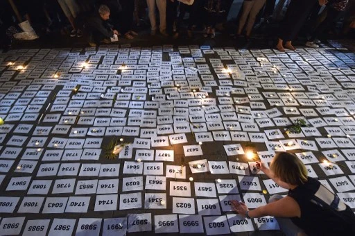 Une femme allume une bougie sur des marque-places numérotés à la veille du 20e anniversaire du massacre de Srebrenica à Belgrade le 10 juillet 2015. (Andréj Isakovic / AFP)